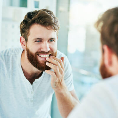 Man looking at teeth in mirror